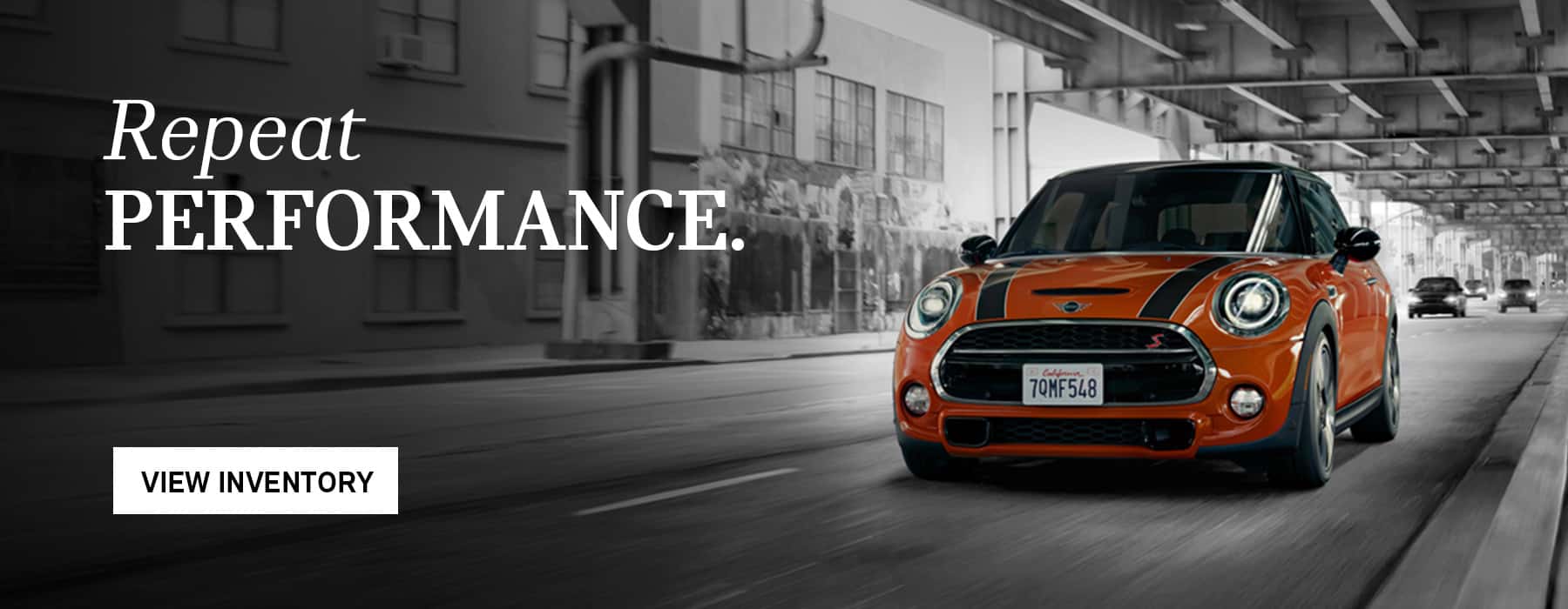 Orange Hardtop Cooper driving down the road.