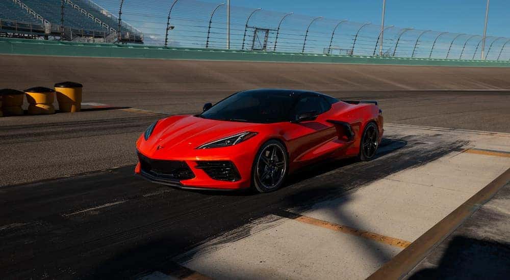 An orange 2021 Chevy Corvette is shown at a staging area ready to drive down a race track.