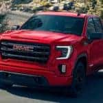 A red 2021 GMC Sierra 1500 Elevation is shown driving around a sharp corner.
