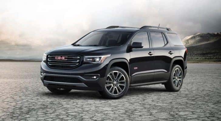 A black 2021 Acadia is parked in a flat desert.