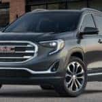 A black 2021 GMC Terrain is parked in front of a brick building after leaving a GMC dealer near you.