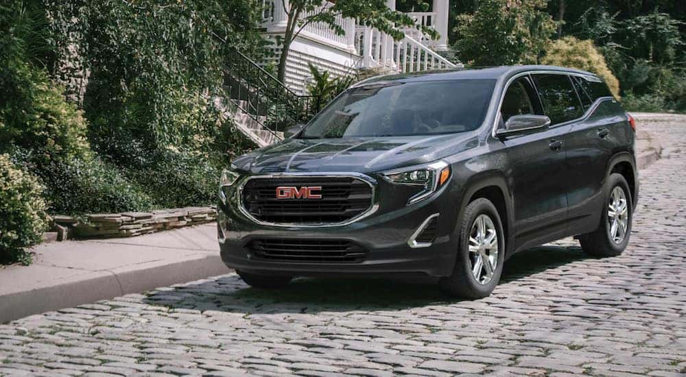 A green 2021 GMC Terrain is driving down a cobblestone road.