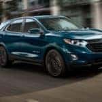 A turquoise 2021 Chevy Equinox is driving through a city after leaving a Murfreesboro Chevy dealer.