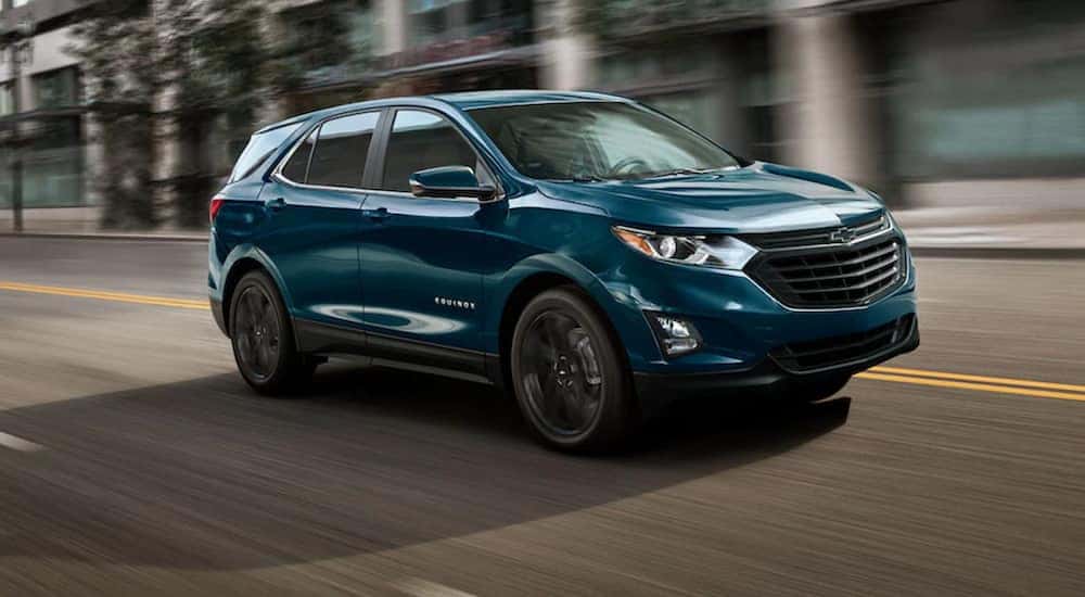 A turquoise 2021 Chevy Equinox is driving through a city after leaving a Murfreesboro Chevy dealer.