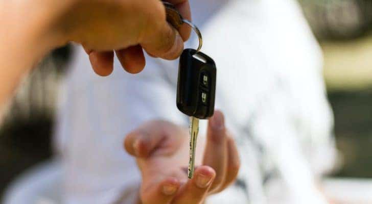 A salesman is passing a key to a car buyer at a Murfreesboro used car dealer.