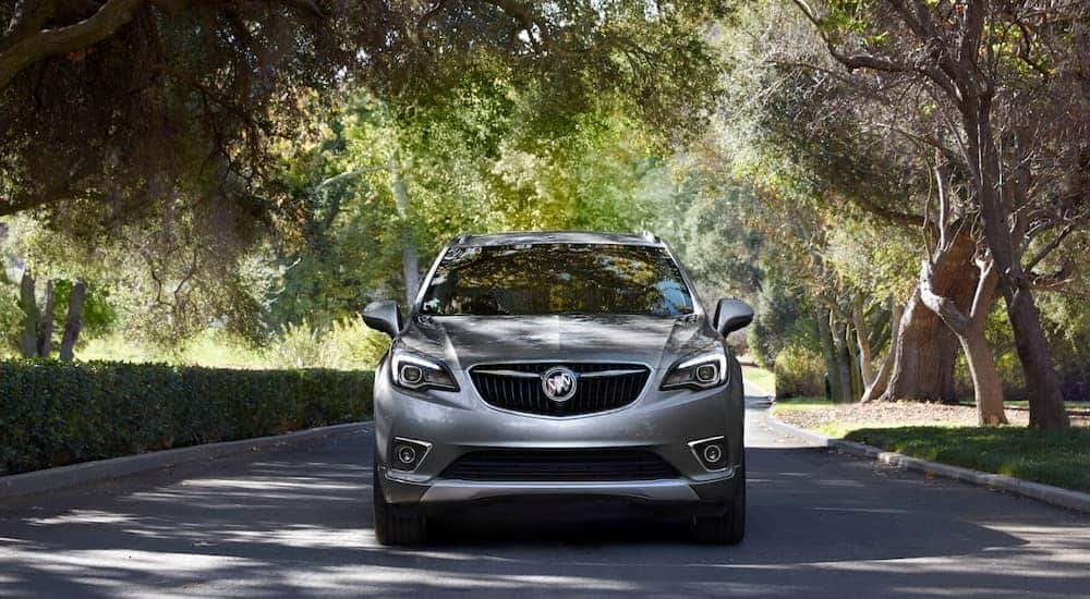 A grey 2020 Buick Envision is shown from the front driving through a city.