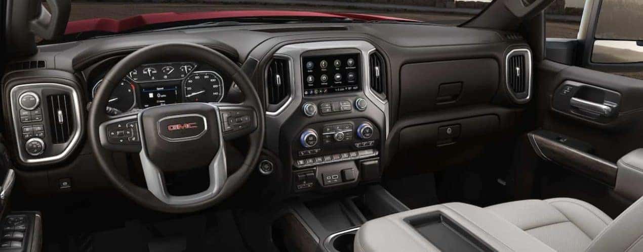 The black interior of a 2022 GMC Sierra 2500HD shows the steering wheel and infotainment screen.