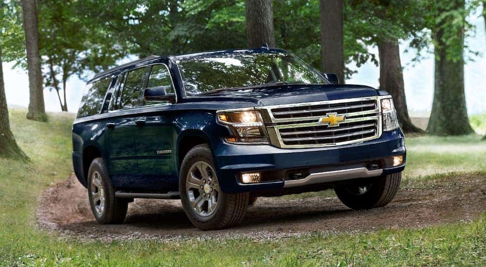 A blue 2020 Chevy Suburban is shown driving on a dirt trail.
