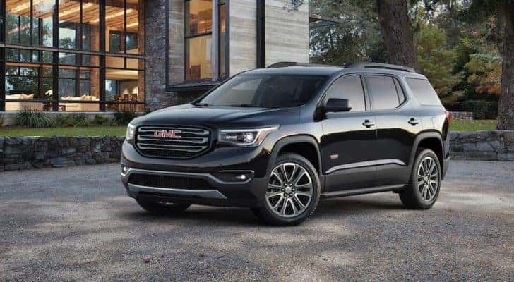 A black 2017 GMC Acadia is parked outside of a modern home.