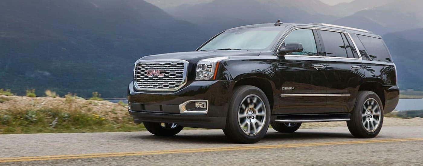 A black 2020 GMC Yukon is shown driving on an open highway.