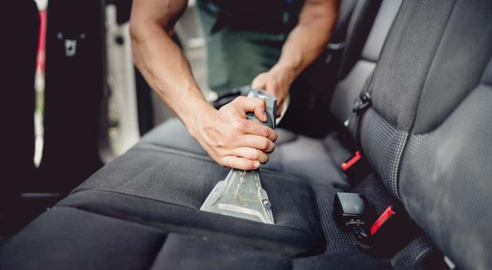 A person is shown vacuuming their car after searching how to "sell my car."