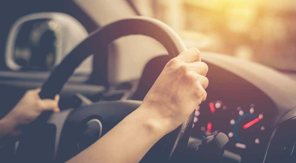 A person is shown driving a car in close up.