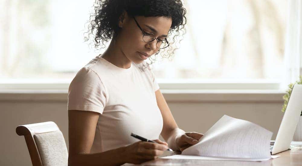 A person is shown completing paperwork to sell your car.