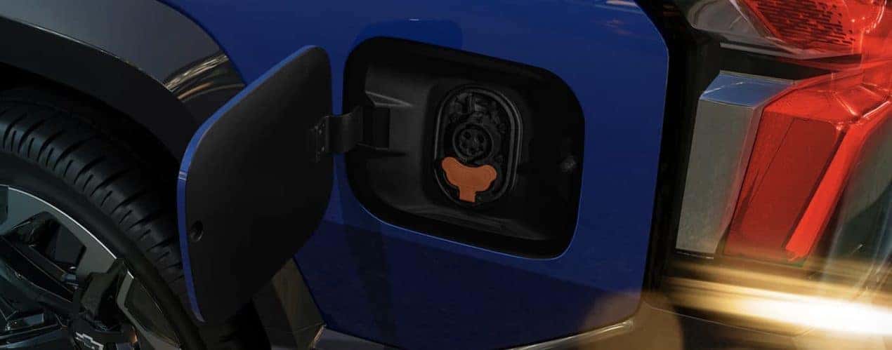 A blue 2024 Chevy Silverado EV shows the charging port in close up.
