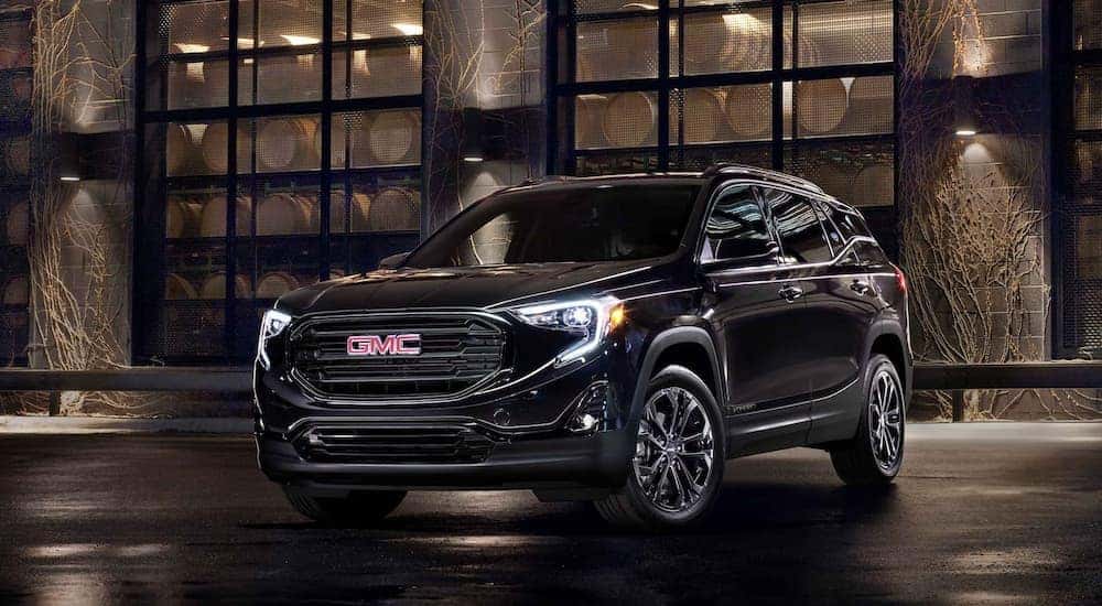 A black 2021 GMC Terrain is shown parked outside of a workshop.