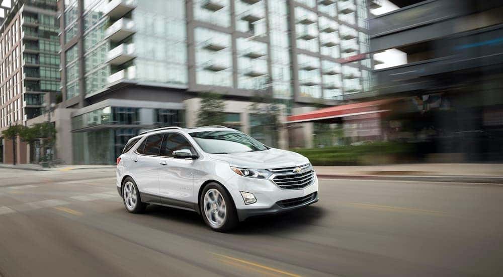 A white 2019 Chevy Equinox is shown driving on a city street.
