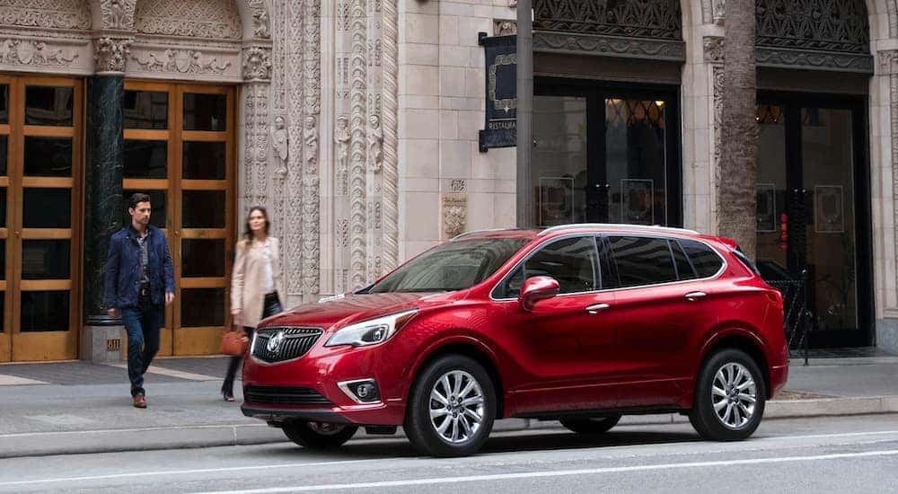 A red 2020 Buick Envision is shown parked outside of a city building.