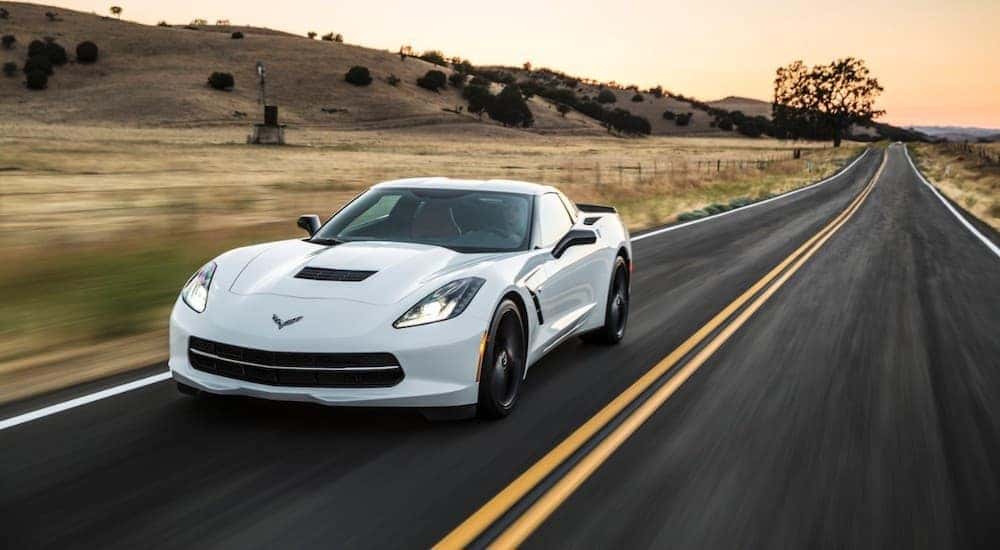 A white 2019 Chevy Corvette is shown from the front at an angle on an open road.