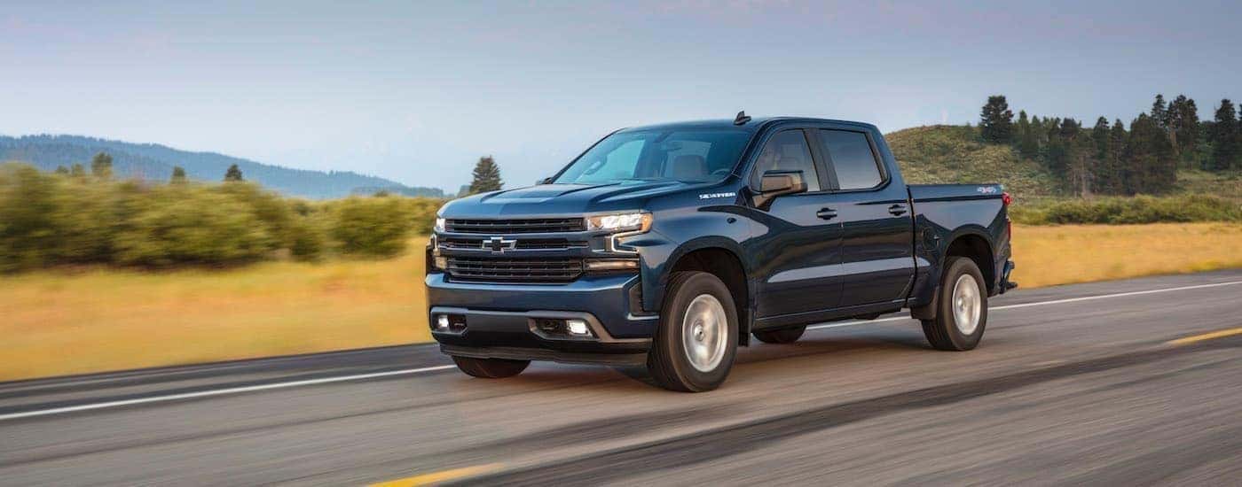 A popular Shelbyville used truck, a blue 2020 Chevy Silverado 1500 is shown driving on an open road.