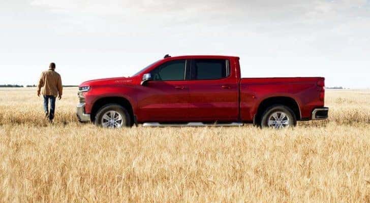 A red 2020 Chevy Silverado 1500 is shown from the side parked in a field.