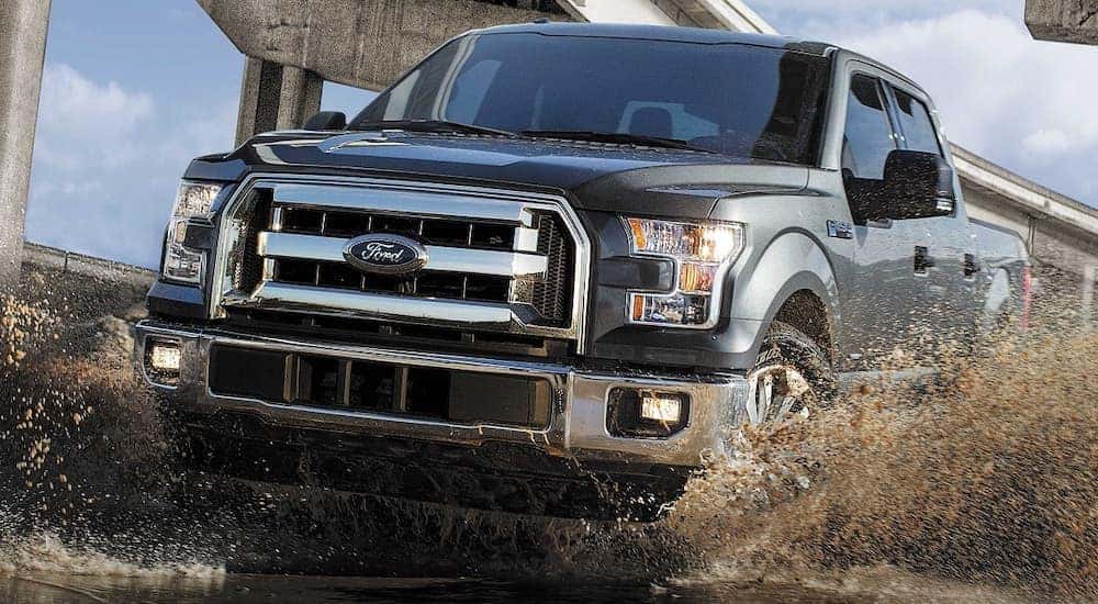 A dark grey 2017 Ford F-150 XLT is shown from the front while driving though mud.