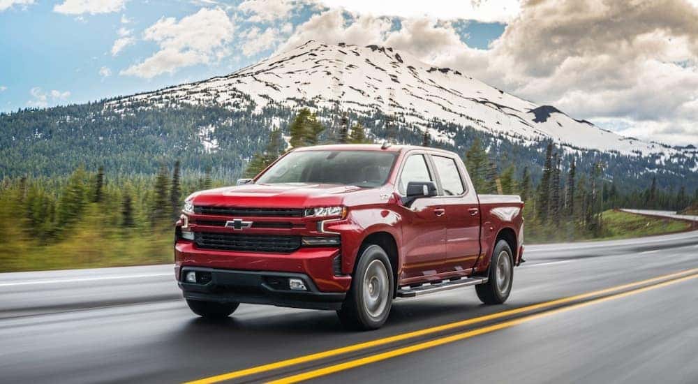 A red 2020 Chevy Silverado 1500 is shown driving on an open road.