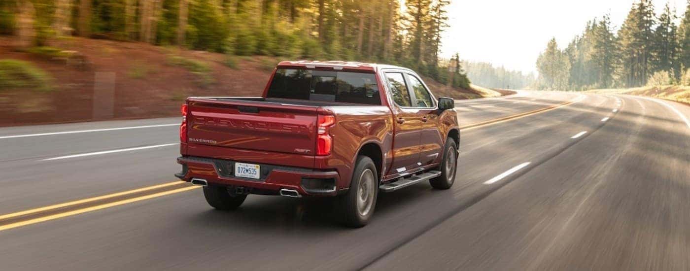 A red 2021 Chevy Silverado 1500 is shown driving to a Murfreesboro used truck dealer.