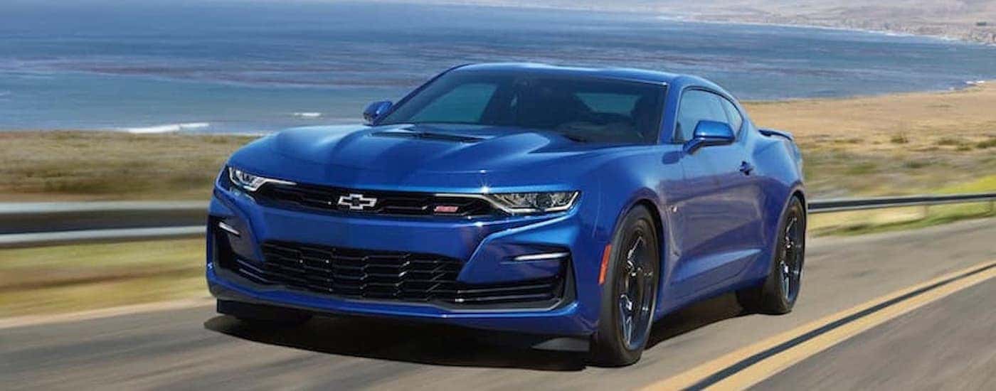 A blue certified 2020 Chevrolet Camaro SS for sale is shown driving on an open road.