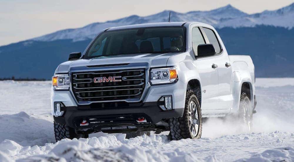 A white 2021 GMC Canyon is shown off-roading in the snow.