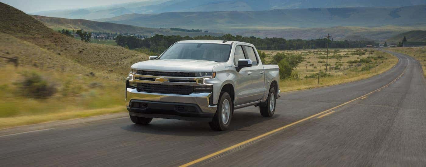 A silver 2019 Chevy Silverado 1500 LT is shown driving on an open road.