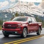 A red 2020 Chevy Silverado 1500 Z71 is shown driving on an open road with a mountain view.