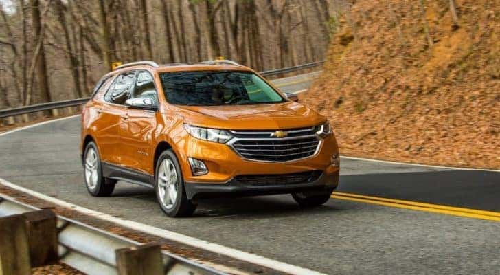 An orange 2019 Chevy Equinox is shown driving on an open road.