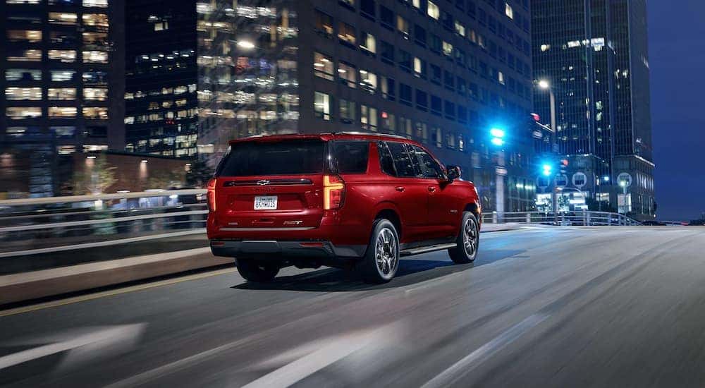 A red 2022 Chevy Tahoe RST is shown driving on a city street after leaving a used Chevy SUV dealer.