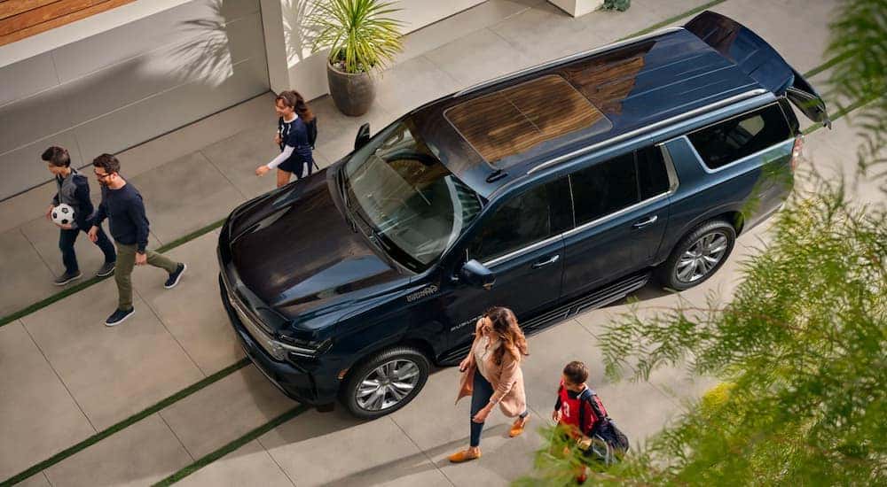 A dark blue 2023 Chevy Suburban High Country is shown from a high angle.