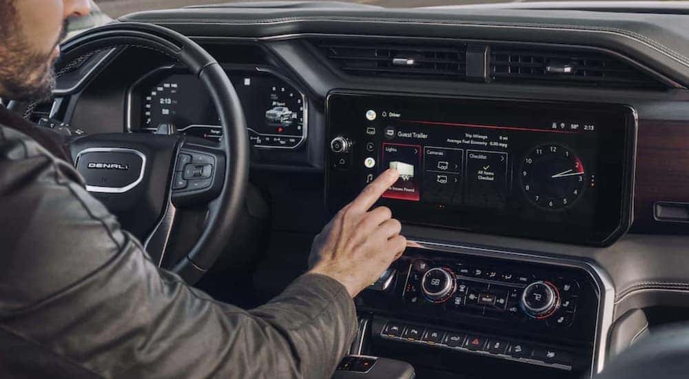A man uses the infotainment screen in a 2023 GMC Sierra 1500 Denali
