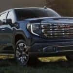 A blue 2023 GMC Sierra 1500 is shown parked in a field.
