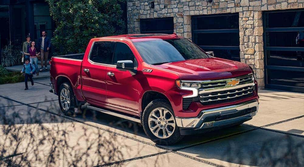 A family walking out to a red 2023 Chevy Silverado 1500 Z71 parked in their driveway