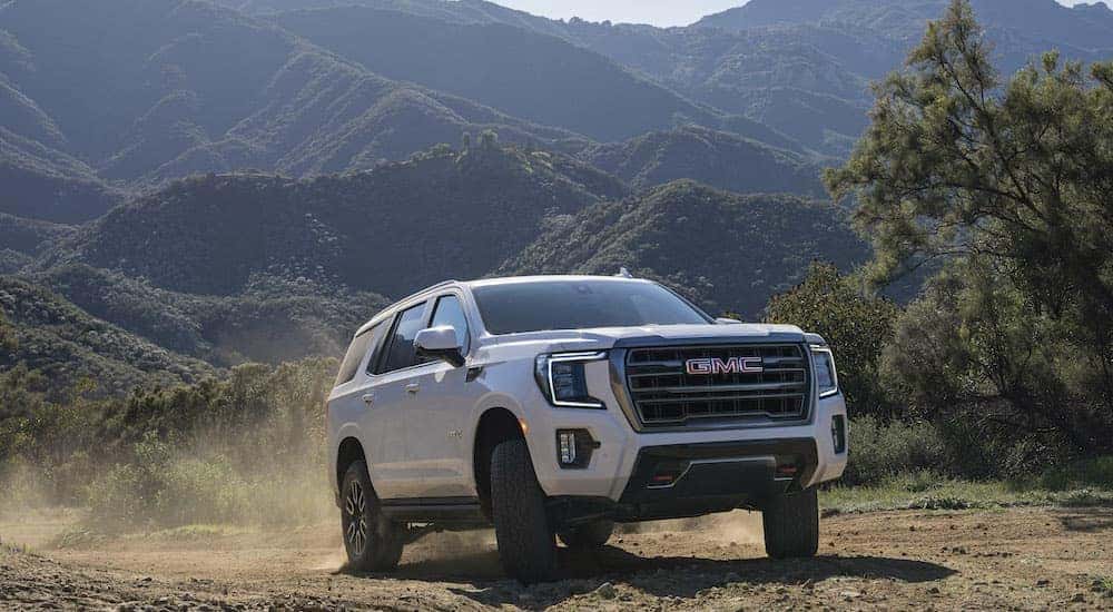 A white 2023 GMC Yukon AT4 off-roading in the mountains