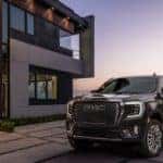A 2023 GMC Yukon Denali parked in front of a modern home overlooking mountains