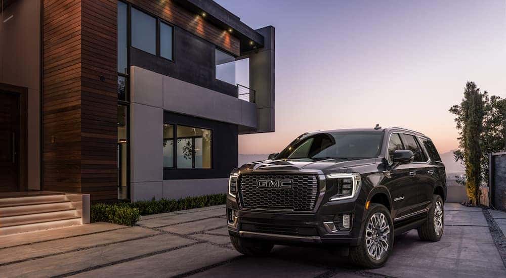 A 2023 GMC Yukon Denali parked in front of a modern home overlooking mountains