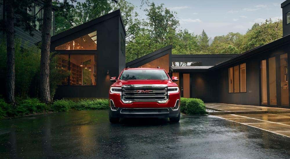 Front view of a red 2023 GMC Acadia parked in front of a modern home