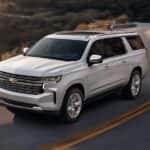 A white 2023 Chevy Suburban driving on a winding mountain road