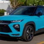 A bright blue 2022 Chevy Trailblazer driving on a tree-lined street