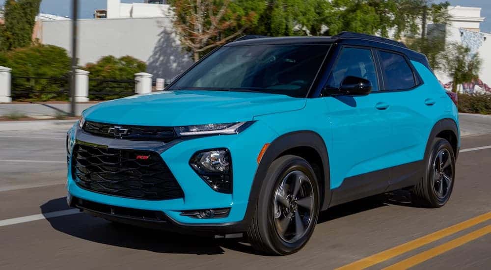 A bright blue 2022 Chevy Trailblazer driving on a tree-lined street