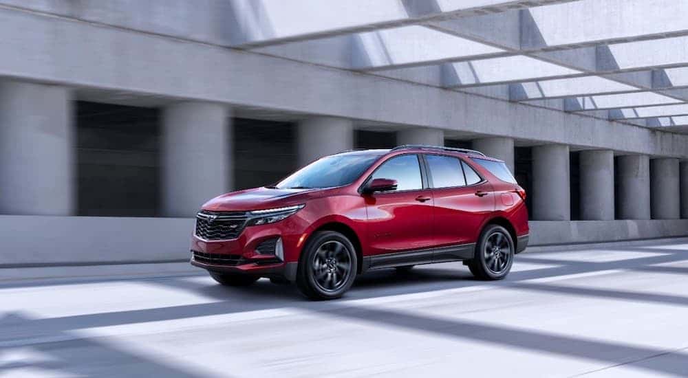 A red 2022 Chevy Equinox RS driving through a bright and modern parking garage
