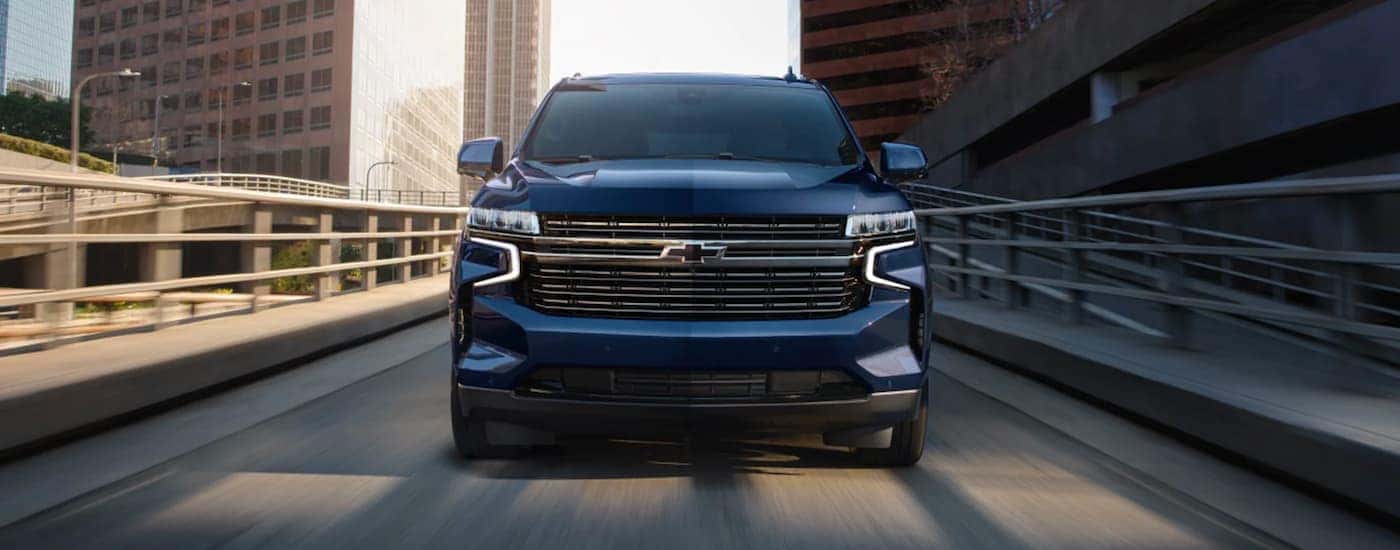 A blue 2023 Chevy Tahoe is shown from the front driving on a ramp.