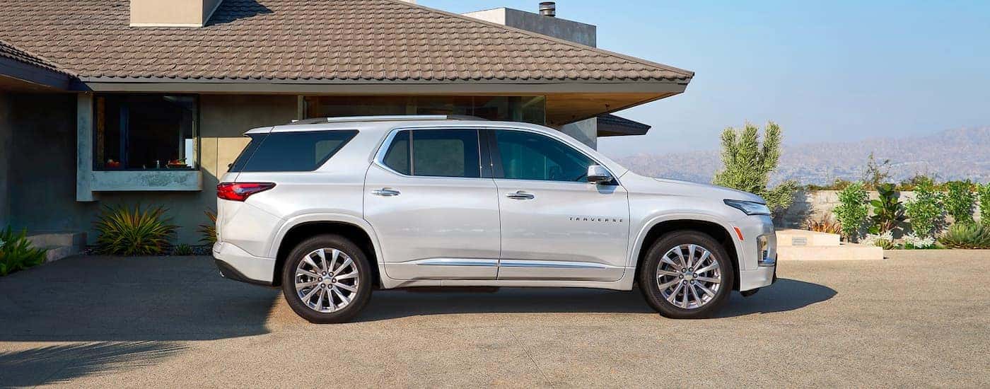 A silver 2023 Chevy Traverse is shown from the side parked in a driveway.
