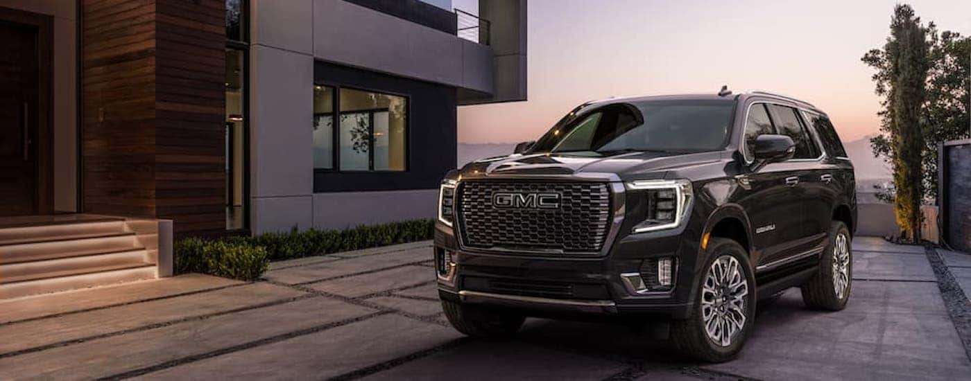 A grey 2023 GMC Yukon Denali Ultimate is shown from the front at an angle while parked in a driveway.