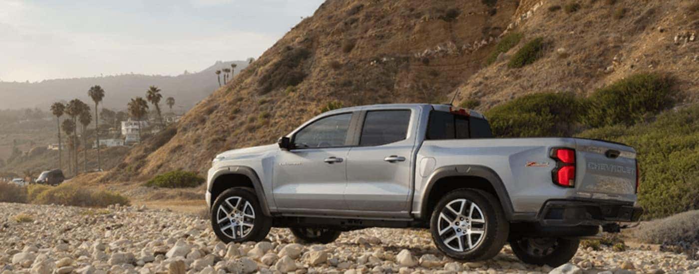 A silver 2023 Chevy Colorado Z71, a popular Chevy truck for sale, is shown parked on a rocky trail.