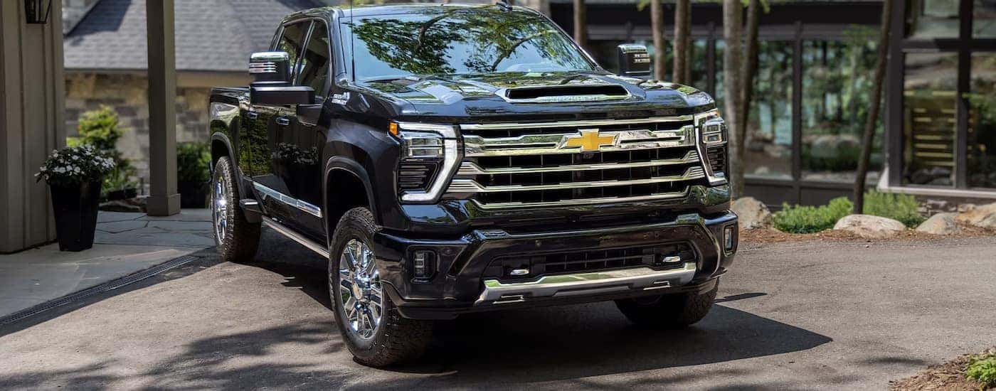 A black 2024 Chevy Silverado 2500HD High Country is shown parked in a driveway.
